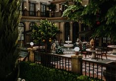 a courtyard with tables, chairs and potted plants in front of an ornate building