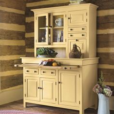 an old fashioned kitchen with yellow cabinets and wood paneling on the wall behind it