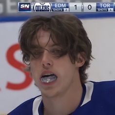 a close up of a person with a toothbrush in his mouth and an ice hockey jersey on