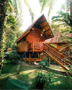 a wooden house surrounded by trees in the jungle with stairs leading up to it's second floor