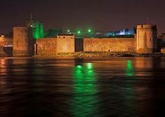 an old castle is lit up at night with green lights on it's walls