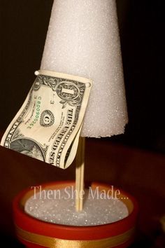 a dollar bill is sticking out of a small stand with a white cone on top