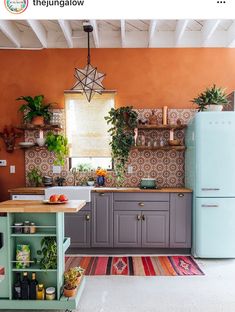 a kitchen with an orange wall and blue refrigerator freezer next to a green island