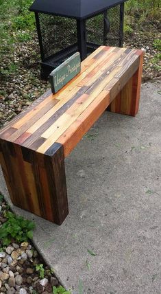 a wooden bench sitting on top of a cement ground next to a metal trash can