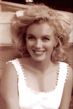 a black and white photo of a woman with blonde hair smiling at the camera,