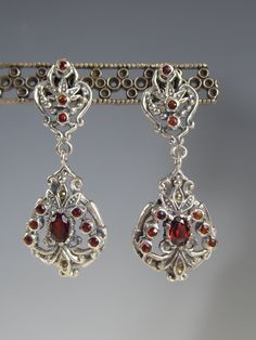 A pretty pair of solid silver garnet set drop earrings. the post fittings attach to a victorian three round cut garnet set open work top from which a open work pendant is attached set with an oval cut central garnet surrounded by six smaller garnets and a couple of marcasites set in which catch the light and sparkle. look very pretty when worn. stamped 925 for silver. hang 4.4cm long.  box for photo's only but will come boxed. Ornate Filigree Garnet Jewelry, Ornate Garnet Filigree Jewelry, Silver Garnet Earrings For Formal Occasions, Oval Garnet Filigree Jewelry, Antique Garnet Earrings, Set Earrings, Girly Accessories, Garnet Earrings, Fancy Jewelry