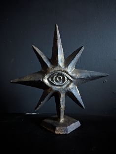 an eye is shown in the center of a metal star sculpture on a black surface