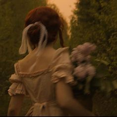 a woman walking down a street with flowers in her hand