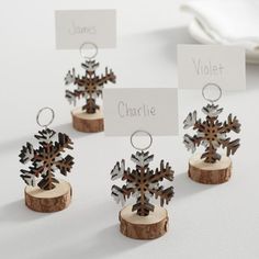 four wooden snowflakes with name tags attached to them sitting on a table