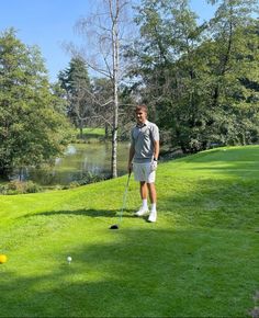 a man standing on top of a lush green field next to a golf ball and tee