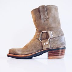 a pair of brown boots with straps and buckles on the side, against a white background