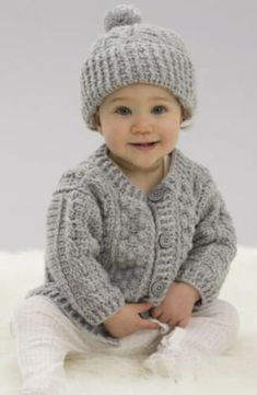 a baby wearing a knitted cardigan and hat with the words aran stitch cardigan & hat