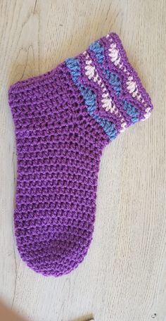 a purple knitted mitt sitting on top of a wooden table