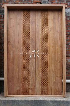 a wooden door with intricate carvings on the outside and inside, in front of a brick wall