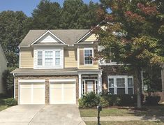 a two story house with garages and trees in the background