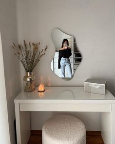 a white dressing table with a mirror on it and a stool in front of it