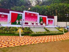 a stage set up for a wedding ceremony with orange and white decorations on the ground