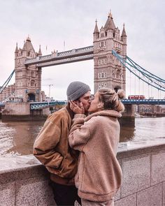 a man and woman kissing in front of the tower bridge