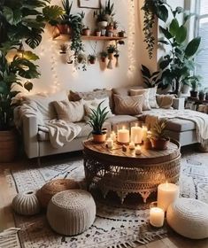 a living room filled with lots of plants and candles on top of a coffee table