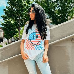 How CUTE! Red, white and blue + smiley + checkerboard = perfect! Part of our Patriotic Collection. Printed with ink on our white soft blend unisex fitted tee. Model is 5'6 wearing a medium. Playful White T-shirt With Smiley Face, Playful White T-shirt For Everyday, White Playful T-shirt With Smiley Face, Playful T-shirt For 4th Of July With Crew Neck, White Smiley Face T-shirt, Playful Crew Neck T-shirt For 4th Of July, Playful White T-shirt For 4th Of July, Fun White Everyday T-shirt, White Graphic Tee With Smiley Face