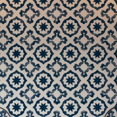 a blue and white patterned wall with two vases on the floor next to it