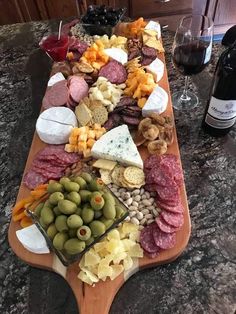 an assortment of cheeses, meats and olives on a wooden platter