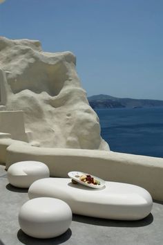 an outdoor seating area overlooking the ocean with white rocks and blue water in the background