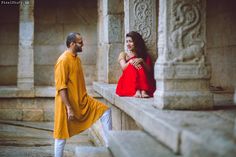 a man and woman standing next to each other in front of some stone pillars with carvings on them