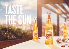 two bottles of beer sitting on top of a table next to glasses and utensils