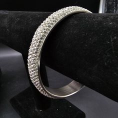 This stainless steel pave rhinestone bangle bracelet fits up to a 9" wrist Silver Crystal Bangle With Bling, Crystal Bangle With Bling, Silver Rhinestone Stainless Steel Jewelry, Cubic Zirconia Bangle Bracelet With Bling, Silver Stainless Steel Jewelry With Rhinestones, Cubic Zirconia Bangle Bracelet, Silver Rhinestone Bangle Crystal Bracelet, Silver Rhinestone Crystal Bangle Bracelet, Party Jewelry With Rhinestones In Stainless Steel