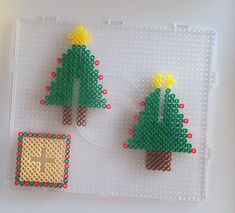 two christmas trees made out of legos sitting on top of a white board with red and yellow dots