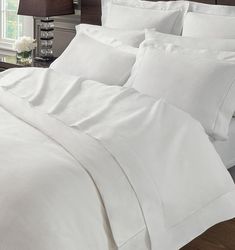 a bed with white sheets and pillows in a bedroom