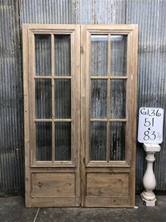 an old wooden double door with two glass doors and a sign on the side of it