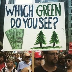 a man holding a sign that says which green do you see?