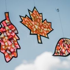 three pieces of art hanging from strings in the air with leaves on them, and one piece of paper cut out to look like an autumn leaf