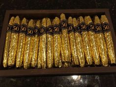 some gold foil wrapped in black and white numbers on top of a brown tray filled with rolls