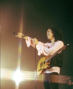 a woman holding a guitar and singing into a microphone