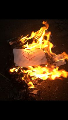 a piece of paper with a heart drawn on it sitting in the middle of a fire