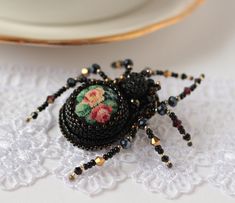 a beaded spider sitting on top of a white doily next to a plate