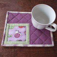 a coffee cup sitting on top of a purple place mat