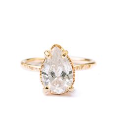 Fresh and dewy, for a lifetime! We love the Summer Rain engagement ring for it's fresh-cut flora feel, romantic and girly and vivacious. A three carat, pear-shaped moissanite, clear and nearly colorless, stands out in a hammered golden halo setting, on a slim and gamine 1.5mm band of burnished yellow gold. Pear Moissanite Nearly Colorless 12x8mm 3ct Hammered Halo Basket Setting Hammered 1.5mm Band 14k Yellow Gold Hammered Engagement Ring, Pear Engagement Ring Halo, Hexagon Engagement Ring, Hammered Wedding Bands, Future Engagement Rings, Pear Shaped Engagement Rings, Basket Setting, Summer Rain, Pear Engagement Ring