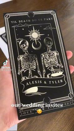 a hand holding up a playing card with skeletons on it