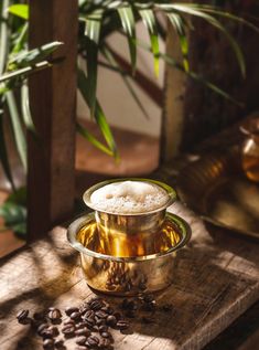 a cup filled with coffee sitting on top of a wooden table next to some plants