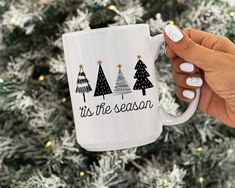 a person holding a coffee mug in front of a christmas tree with its season written on it