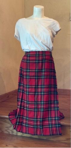 This is a pre-owned red, black, yellow, and green plaid kilt skirt. It is made of pure new wool and has a black leather side buckles. The skirt has a wrap-around design and is pleated. It measures approximately 14 inches across the waist and 28 inches in length. The skirt is in good condition with no visible tears or stains. The skirt is a great option for anyone looking for a traditional kilt skirt or college academia look. Bin 317 Academia Look, Kilt Skirt, Wool Plaid, Green Plaid, Kilt, Red Plaid, Pleated Skirt, Scotland, Black Leather