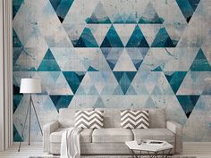 a living room with a couch, table and wallpaper that has blue triangles on it