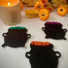 three crocheted tea cosies next to a candle