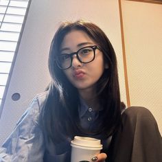 a woman with glasses holding a cup of coffee