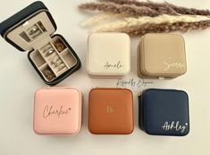 four small personalized jewelry boxes with their names on the front and bottom, along with an open ring box