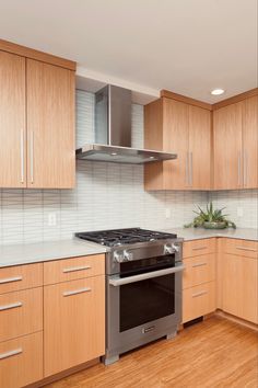 an empty kitchen with wood cabinets and stainless steel stove top oven in the center area